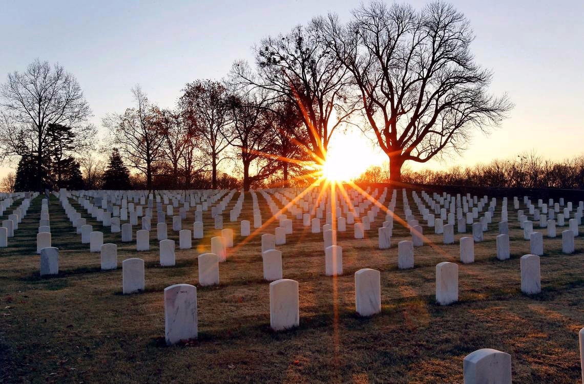 Rows of headstones at Camp Nelson National Cemetery under a golden dawn